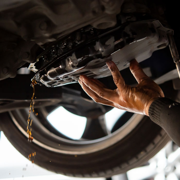 car mechanic draining transmission fluid